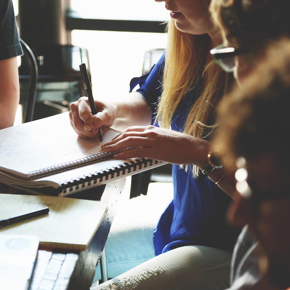 Picture of people writing on a notebook